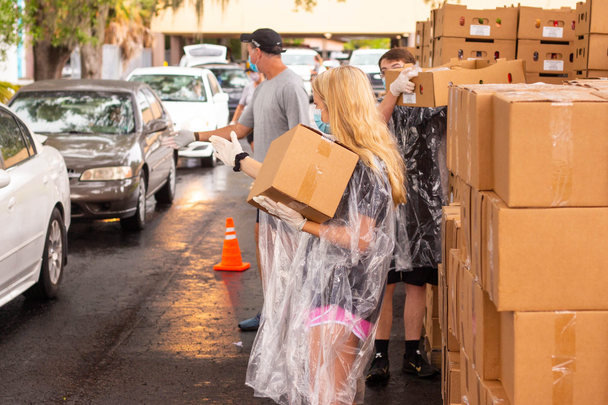 Volunteers motioning for cars to pull up so they can place boxes of food into their trunks