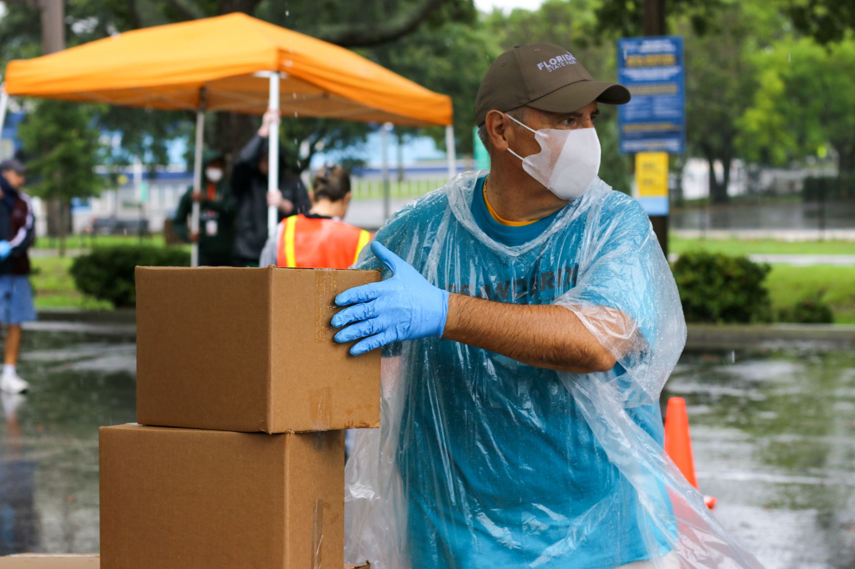 Volunteer handing out boxes of food in the rain