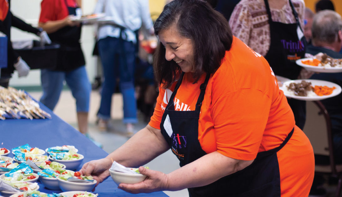 Woman gathers salads to hand out at Trinity Cafe