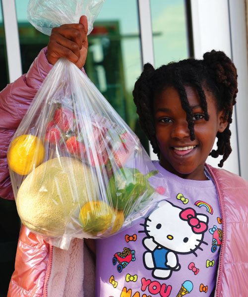 Young girl holding a bag of fruits and vegetables
