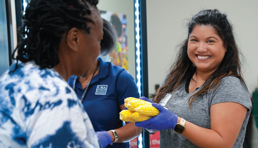 Volunteer handing corn to a neighbor